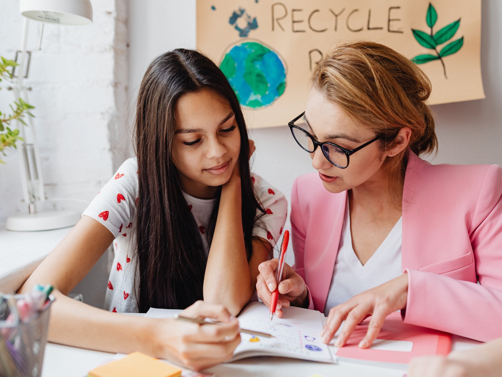 Nachhilfelehrer und Schüler lernen gemeinsam an einem Tisch